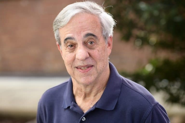 Gregory Squires is an older white man with white hair wearing a blue collared shirt 