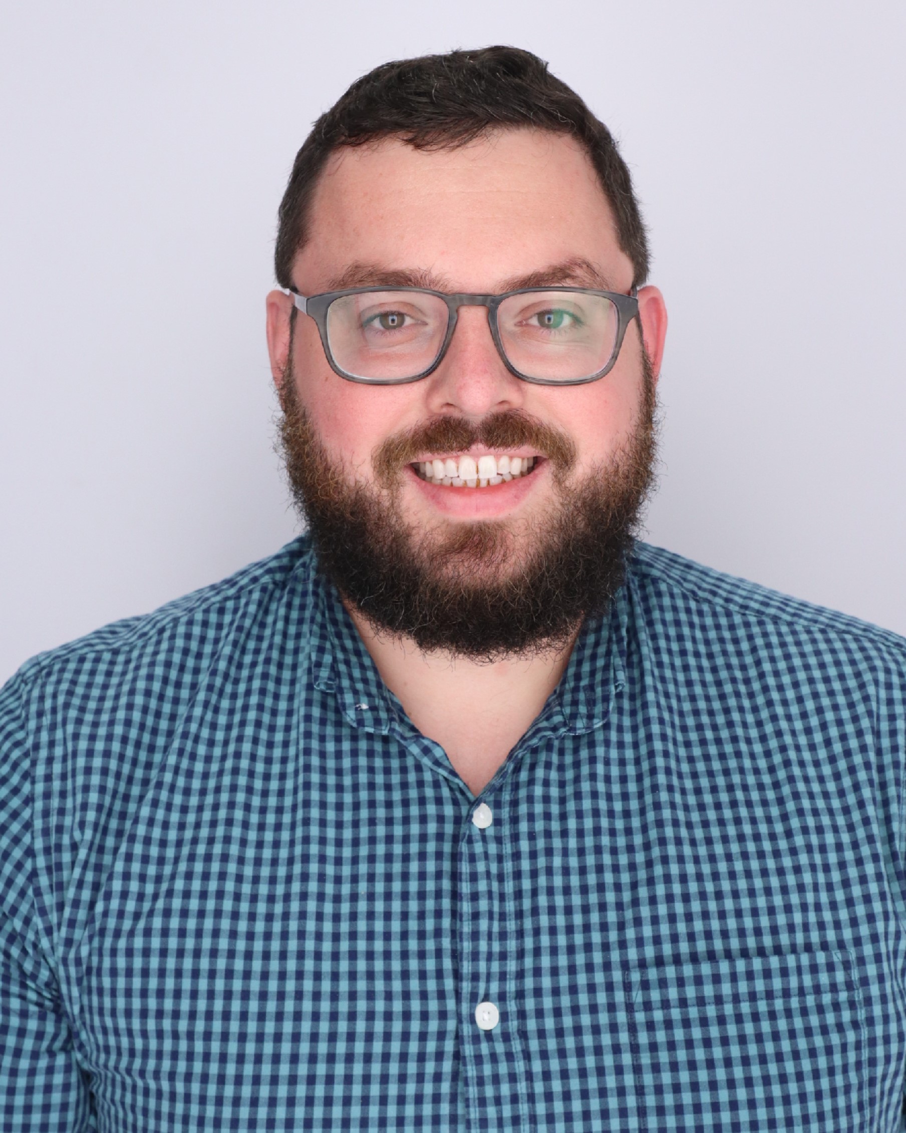 Matthew Kafafian is a white man with a beard and brown hair. He is wearing rectangular glasses and a plaid shirt. 