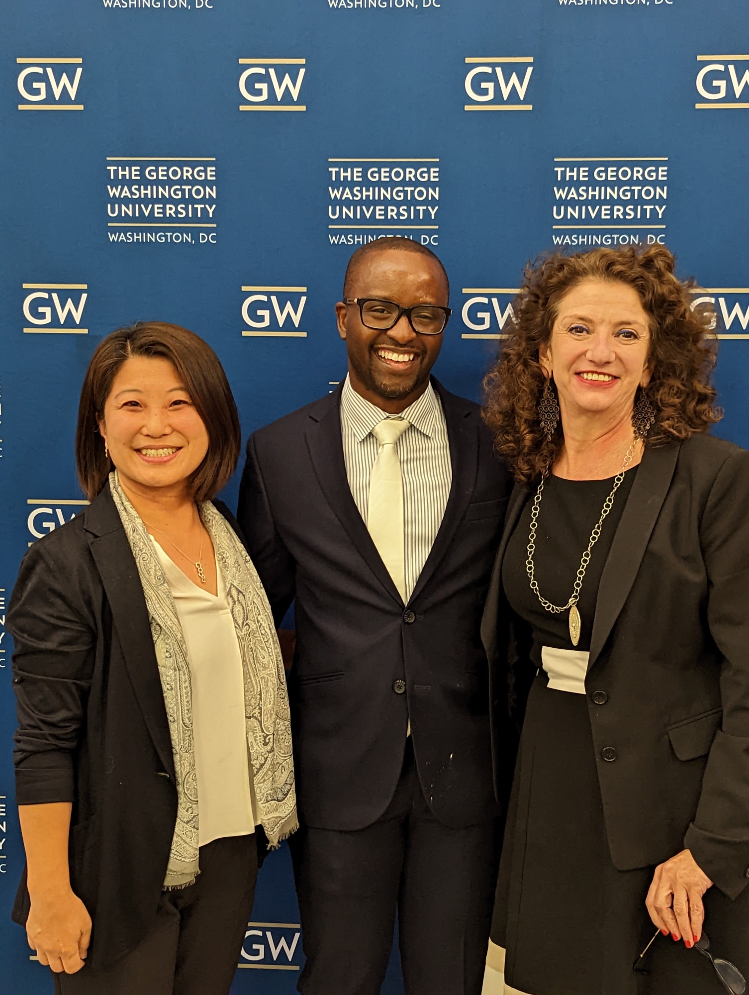 Fran Buntman, Hiromi Ishizawa, and Antwan Jones in front of a blue backdrop with the GW logo