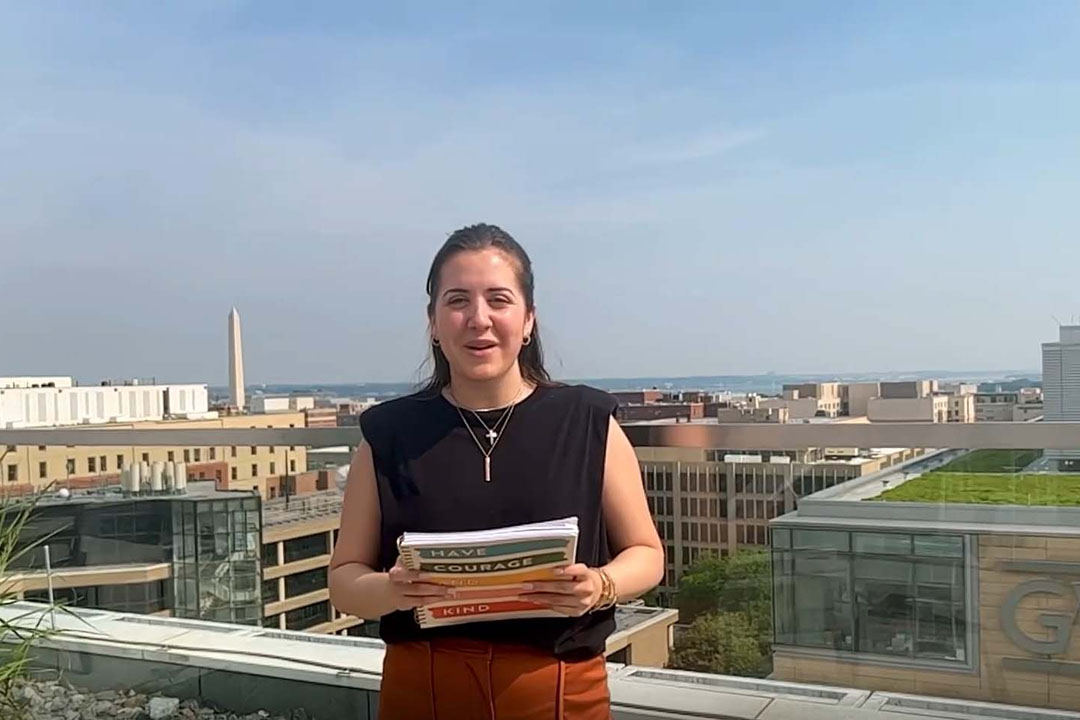 A Sociology student on a rooftop smiling with the Washington Monument in the background