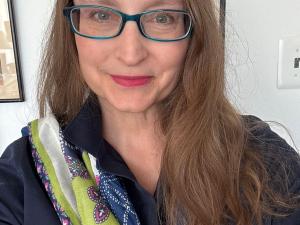 Michelle is a white woman with long brown hair and dark blue glasses