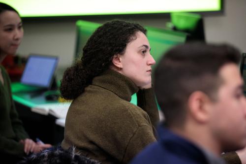 A graduate sociology student sits at a computer and looks at the front of the classroom