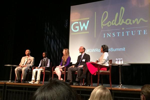 A group of five panelists including Chelsea Clinton sit on a stage with the words "GW" and "Rodham Institute" behind them.